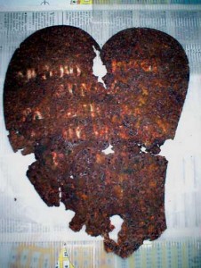 Figura 4. Placa en forma de corazón con restos de escritura hallada sobre una cruz de hierro forjado en el momento de la perforación de la pared de la bóveda de Facundo Quiroga