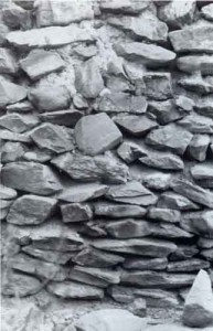 Superposición en una misma pared de dos tipos de aparejos de piedra: abajo lajas planas y arriba piedras irregulares unidas entre si con barro.